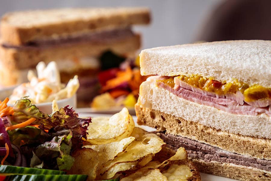 A sandwich with sliced ham and pickle, served on bread with a spread of mayonnaise.